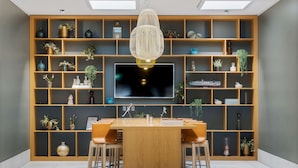 A modern living room with a wooden TV stand, a large flat-screen TV, and a dining table with chairs. - Best Western Plus Airport Hotel Copenhagen (Kastrup)