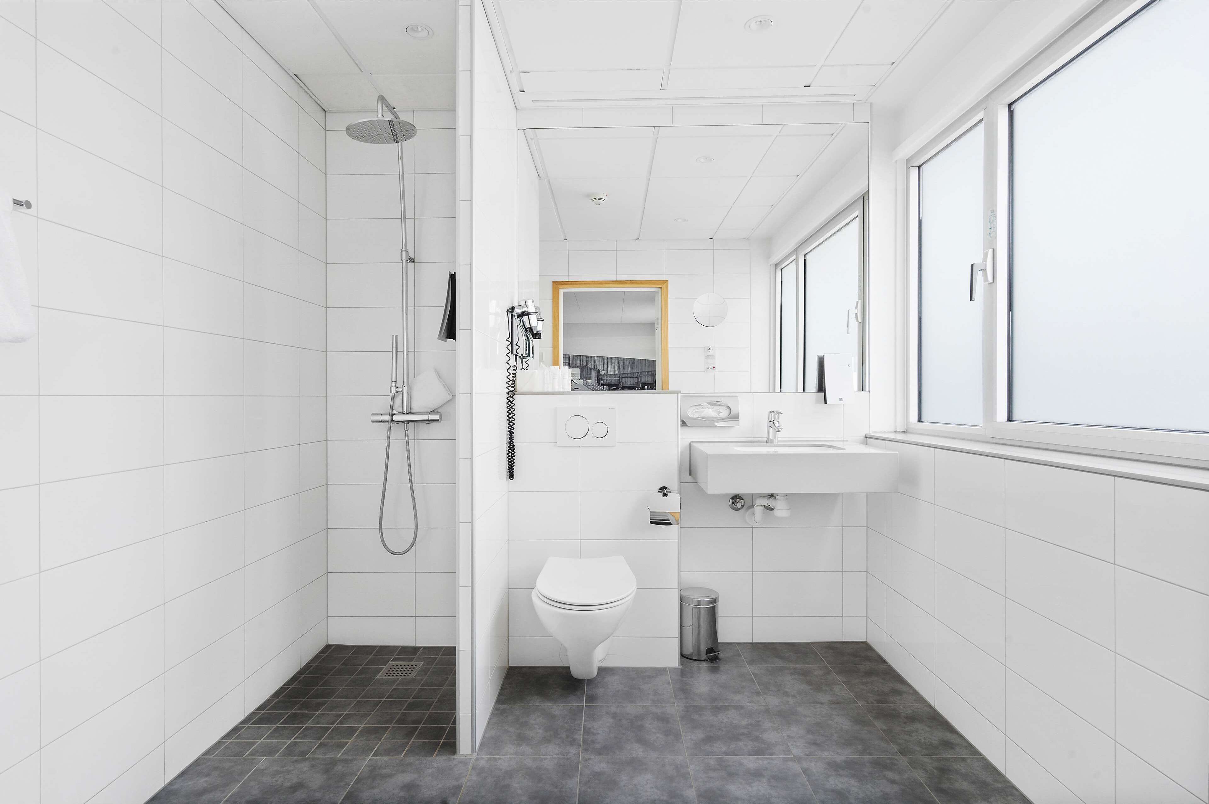 Et moderne badeværelse med bruser, toilet og vask.