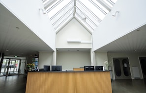 A reception desk with a modern design, a skylight, and a view of the street outside.