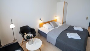 Una habitación de hotel con cama, una silla, una mesita y una mesita de noche.