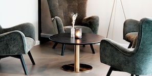 A modern interior with a round table, four grey upholstered chairs, and a vase with dried plants.