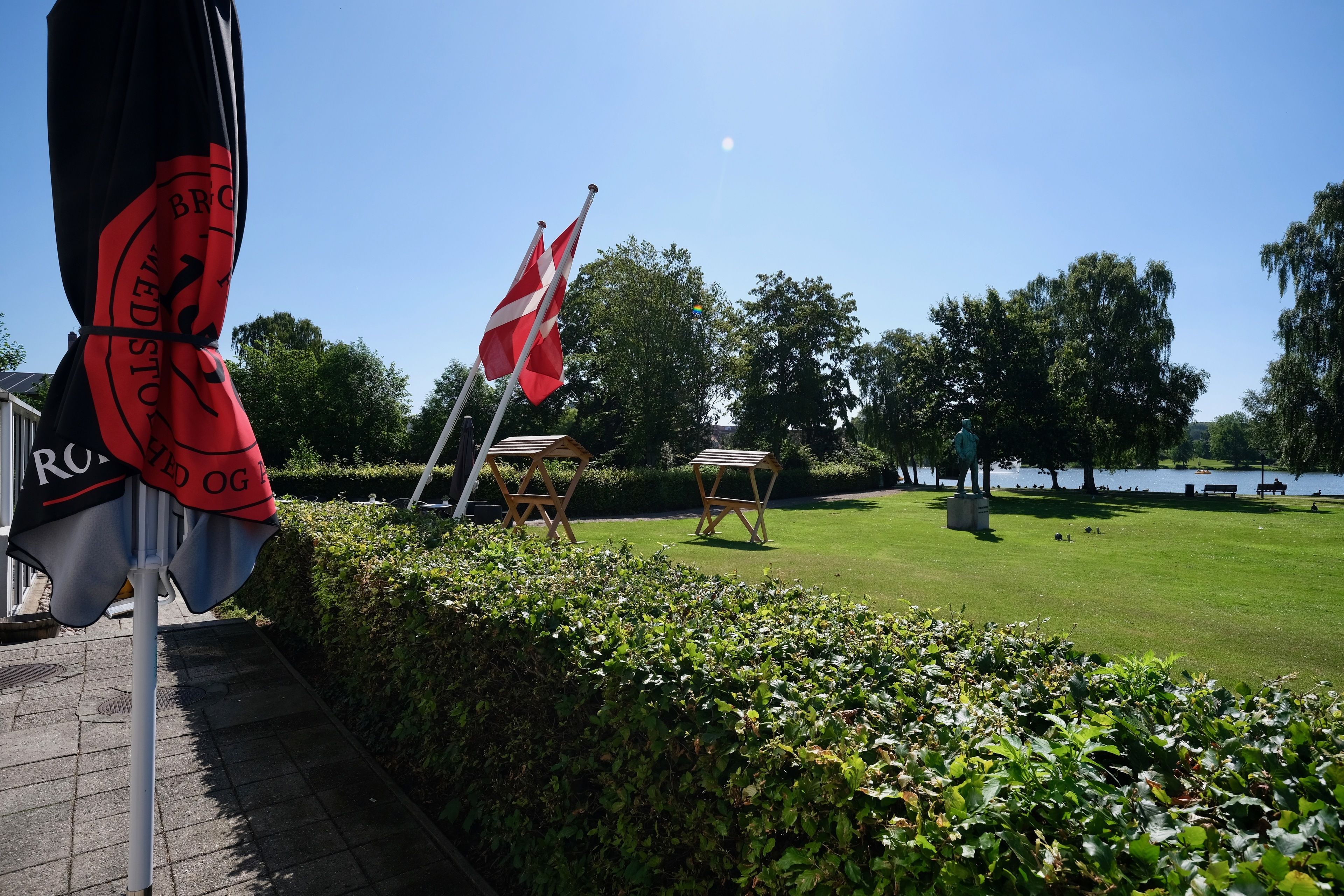 En park med flag, statue og et vandareal.