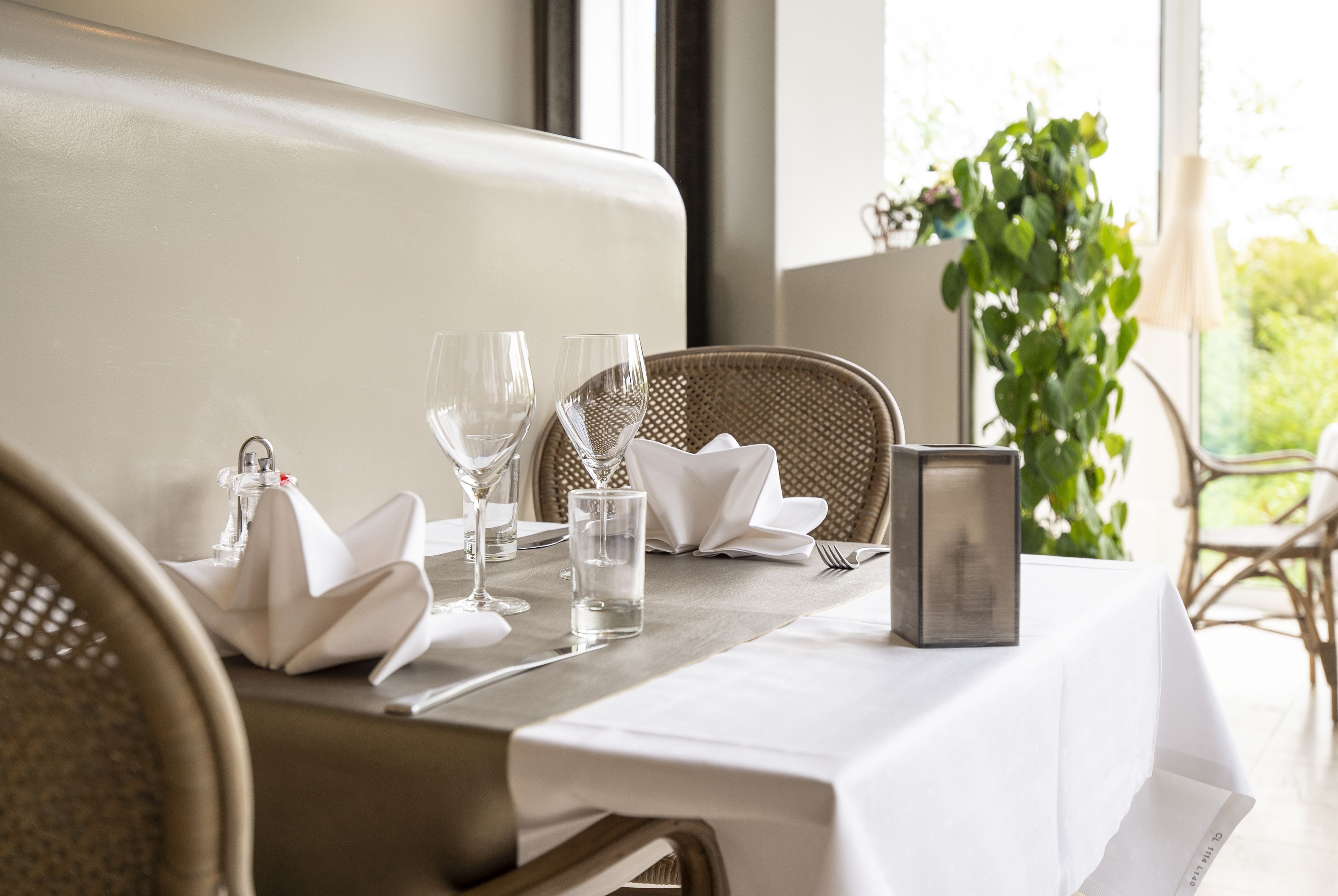 A dining table set with white tablecloth, glassware, and a candle.