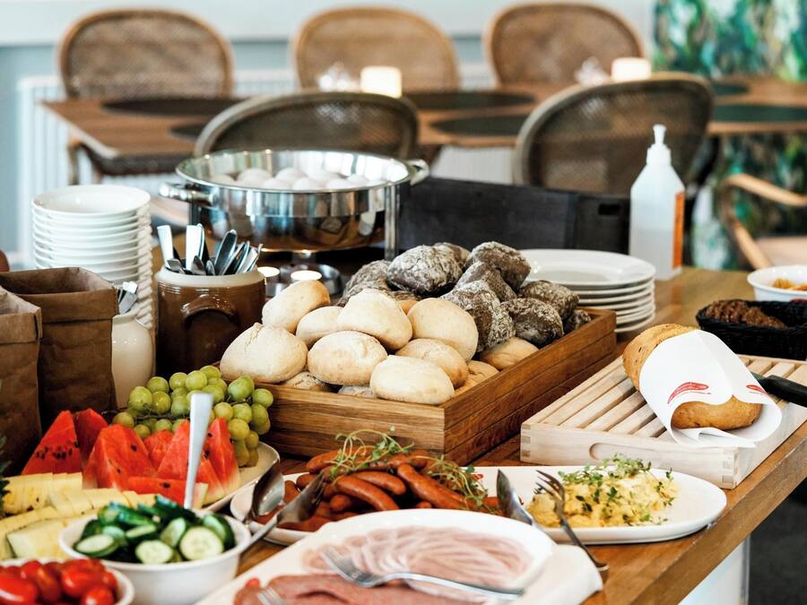 A buffet table with various food items including bread, meats, fruits, and vegetables.
