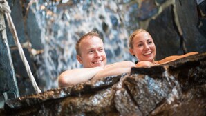 Dos personas en un jacuzzi de paredes de piedra con decoración rústica.
