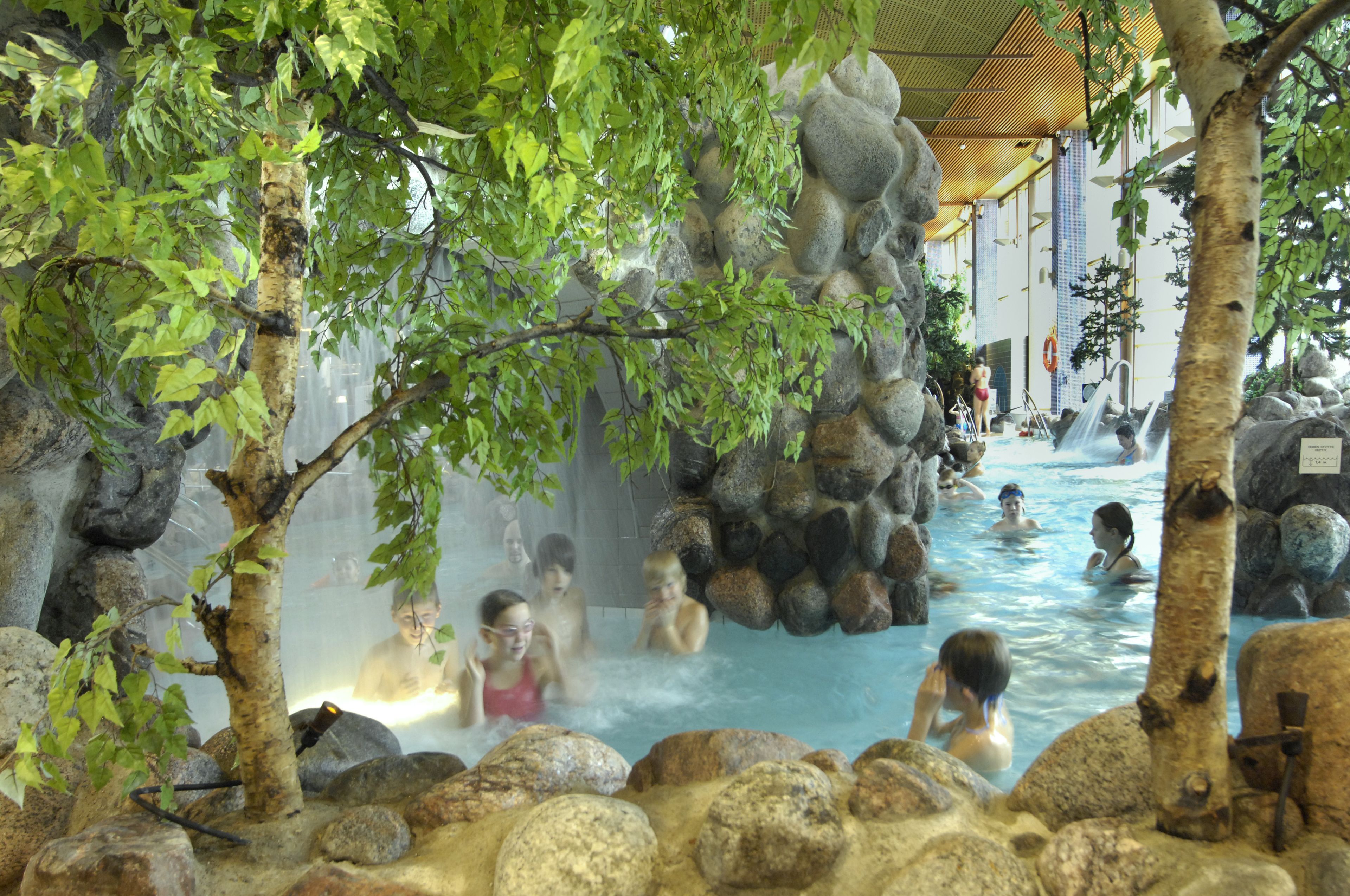 An indoor hot spring area with multiple pools surrounded by rocks and trees.