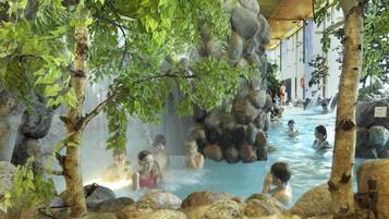 An indoor hot spring area with multiple pools surrounded by rocks and trees.