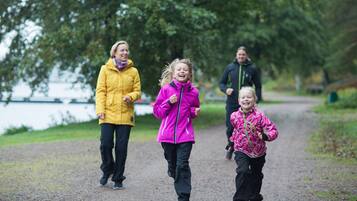 Three people jogging on a gravel path with a lake in the background.