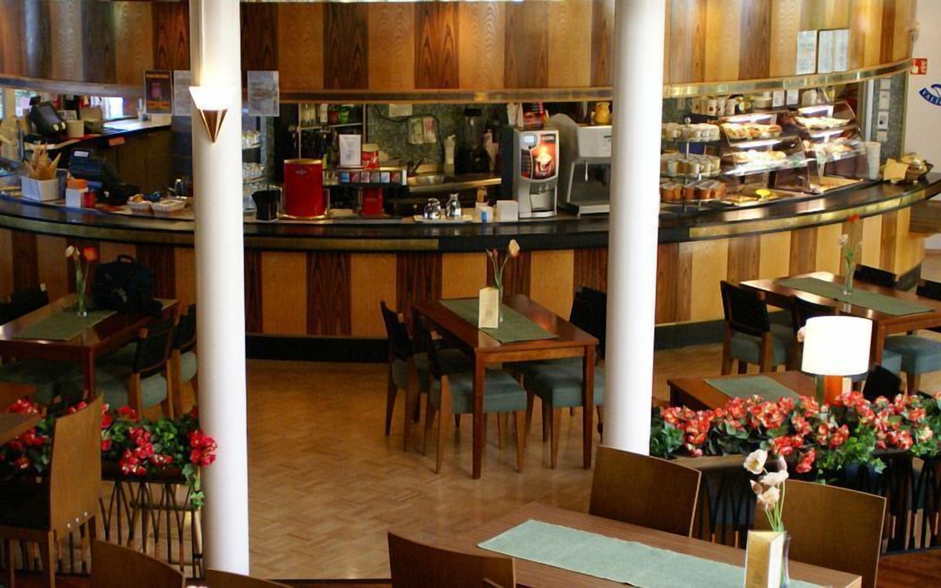 Ein Restaurant mit Holzwandverkleidung, einer Theke mit verschiedenen Speisen und Tischen mit Stühlen.