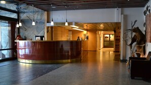 Un espace d’accueil doté d’un comptoir incurvé, d’un éclairage suspendu et d’une enseigne indiquant « Réception ».