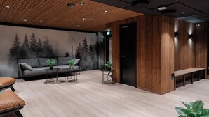Un intérieur moderne avec un plafond en bois, un canapé, un banc et une fresque murale représentant des arbres.