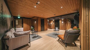 Un hall d’entrée moderne avec des panneaux de bois, un comptoir d’accueil et des espaces de détente.