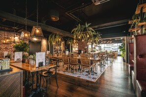 A restaurant with wooden tables and chairs, hanging pendant lights, and brick walls. - Original Sokos Hotel Koljonvirta (Iisalmi)