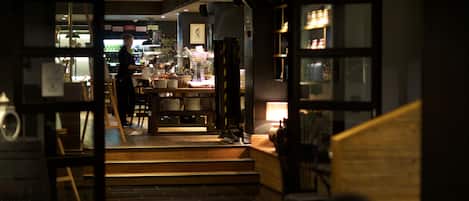 Un interior de restaurante con una zona de bar, mesas y sillas.