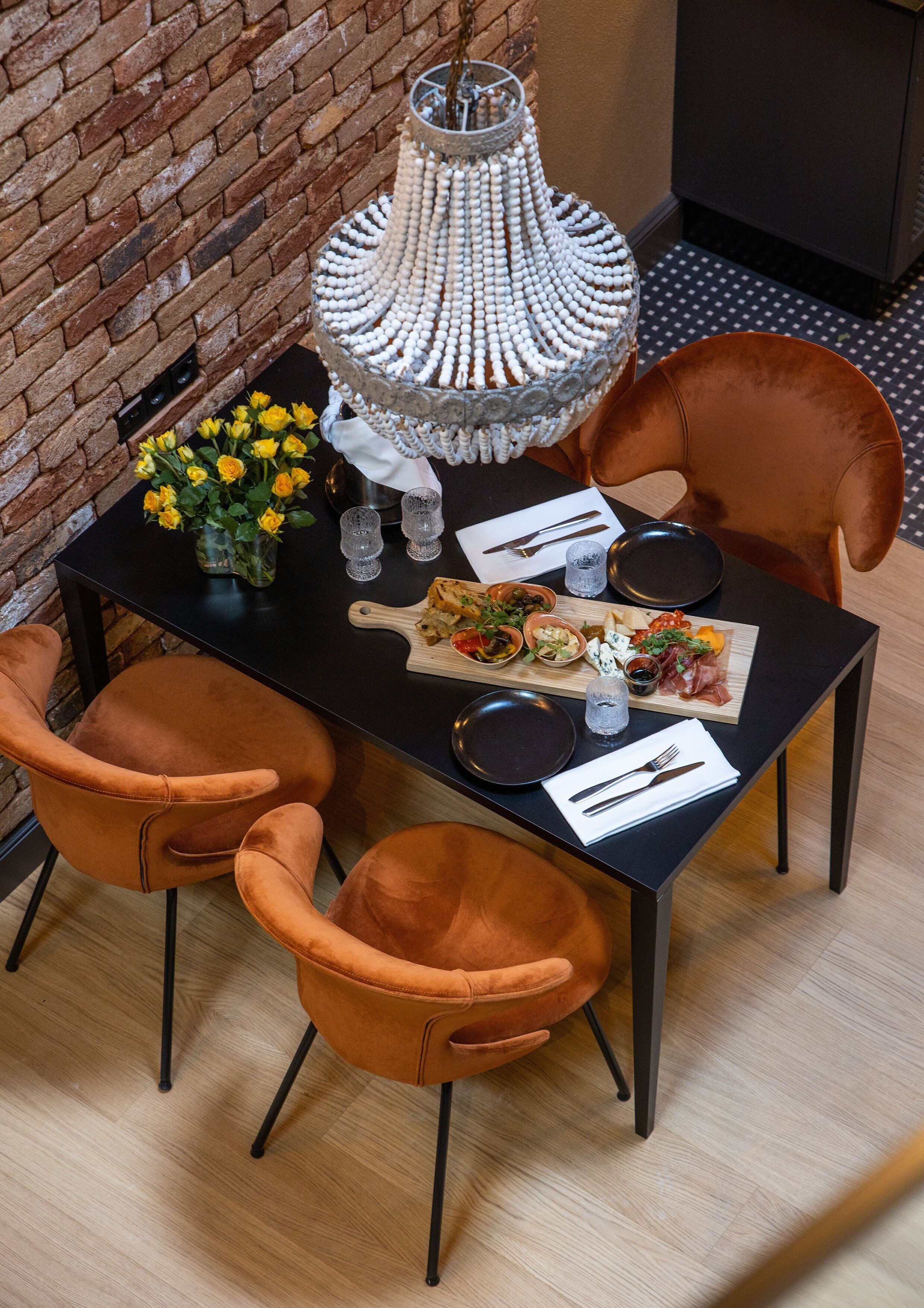 A dining table with a chandelier, two chairs, and a variety of food items.