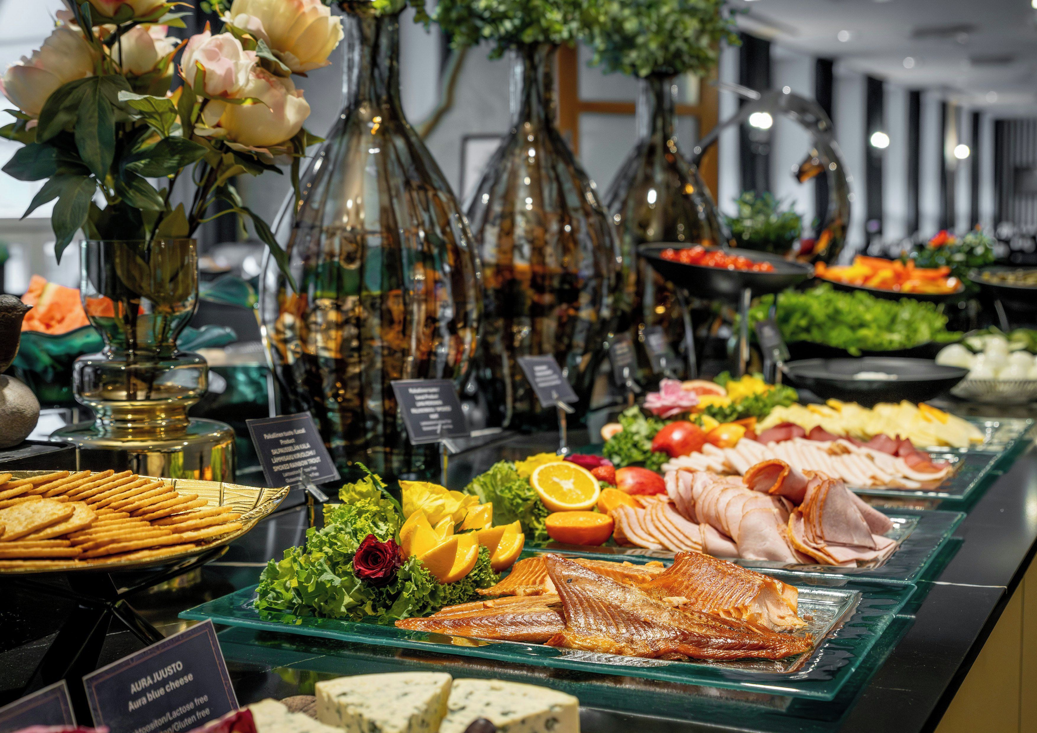 Un bufé con diversos alimentos, incluyendo pescado, queso y frutas.