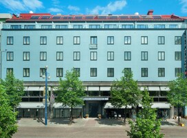 Ein mehrstöckiges Hotel mit einheitlicher Fassade, einem Restaurant im Erdgeschoss und blauem Himmel.
