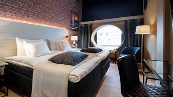 Et hotelværelse med en seng, et rundt spejl, en stol og en lampe.