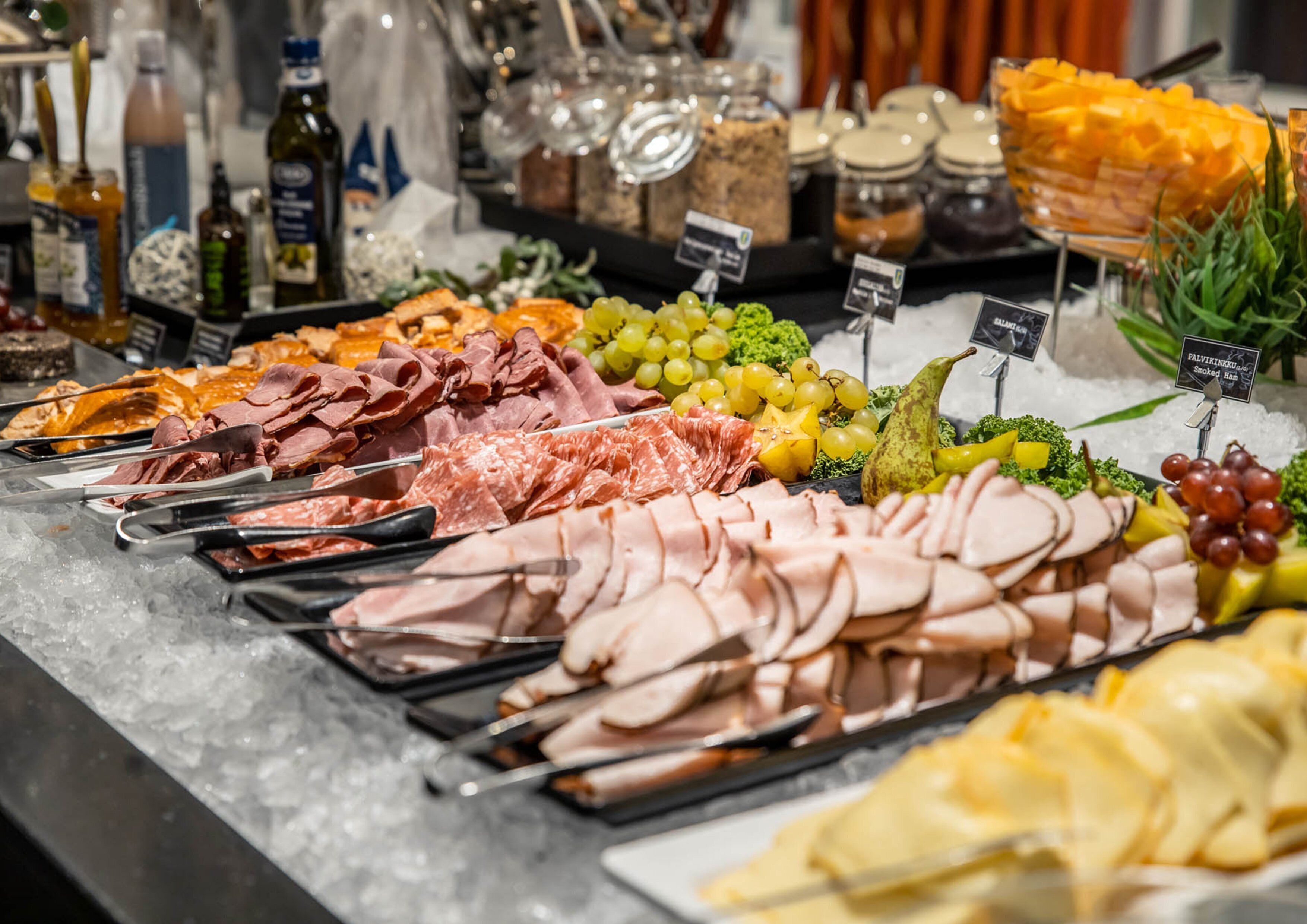 A buffet with various meats, cheeses, and fruits.