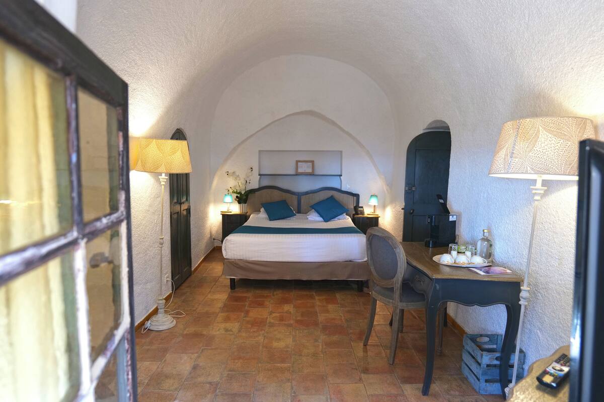 A bedroom with a bed, bedside tables, a desk, and a chair.