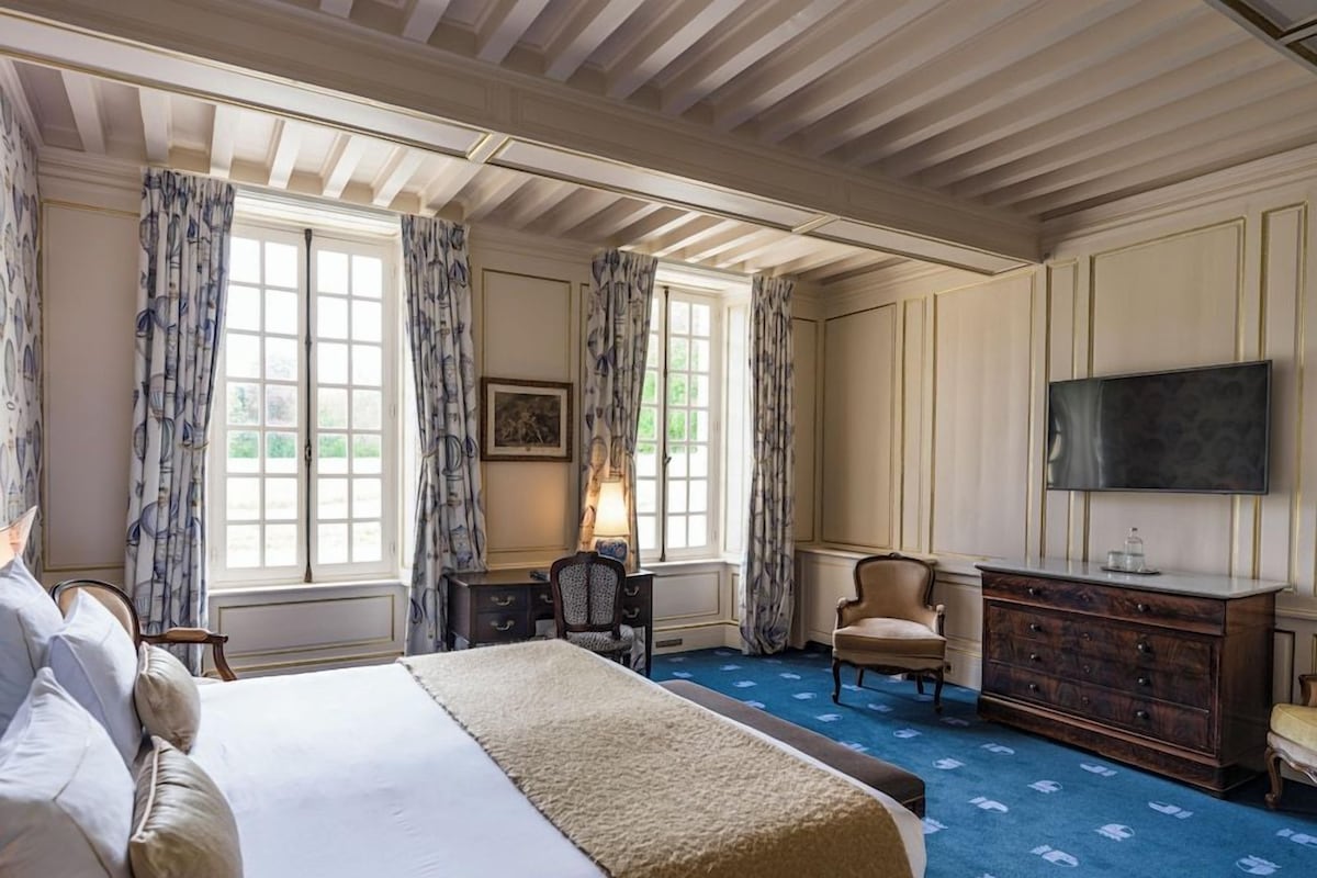 Una habitación de hotel con una cama grande, un escritorio, una silla, un aparador y una televisión.