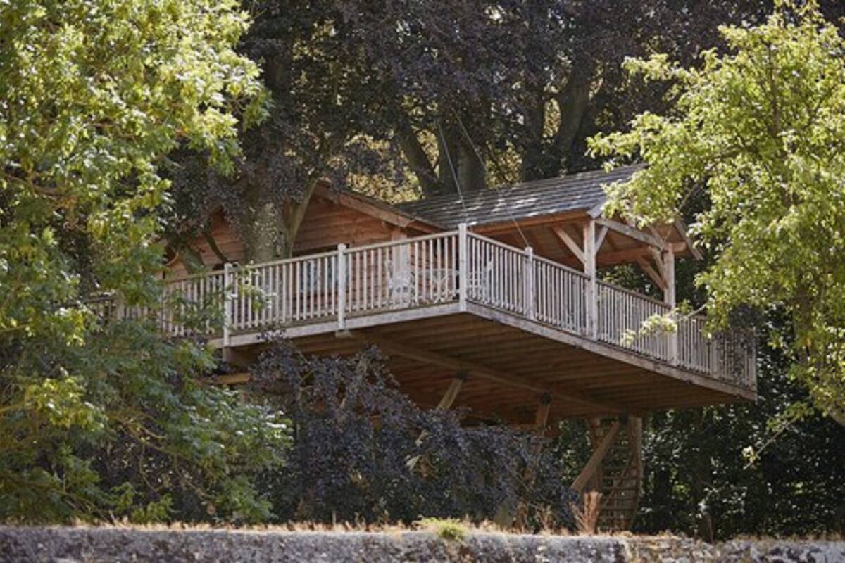 A wooden cabin with a balcony, surrounded by trees.