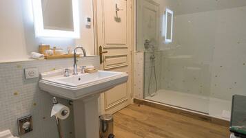 Un bagno con lavandino, specchio, doccia e pavimento in legno.
