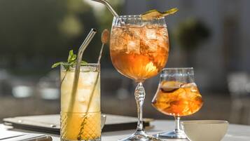 Três copos com bebidas geladas sobre uma mesa, com uma chávena e um telemóvel.