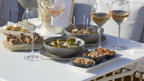 Un tavolo apparecchiato all'aperto con una bottiglia di vino, bicchieri e diversi piatti.