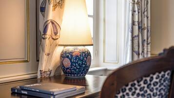 Una lámpara con estampado floral sobre una mesa de madera, un libro y una silla estampada.