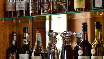 A bar with multiple shelves of liquor bottles and a rack of wine glasses.
