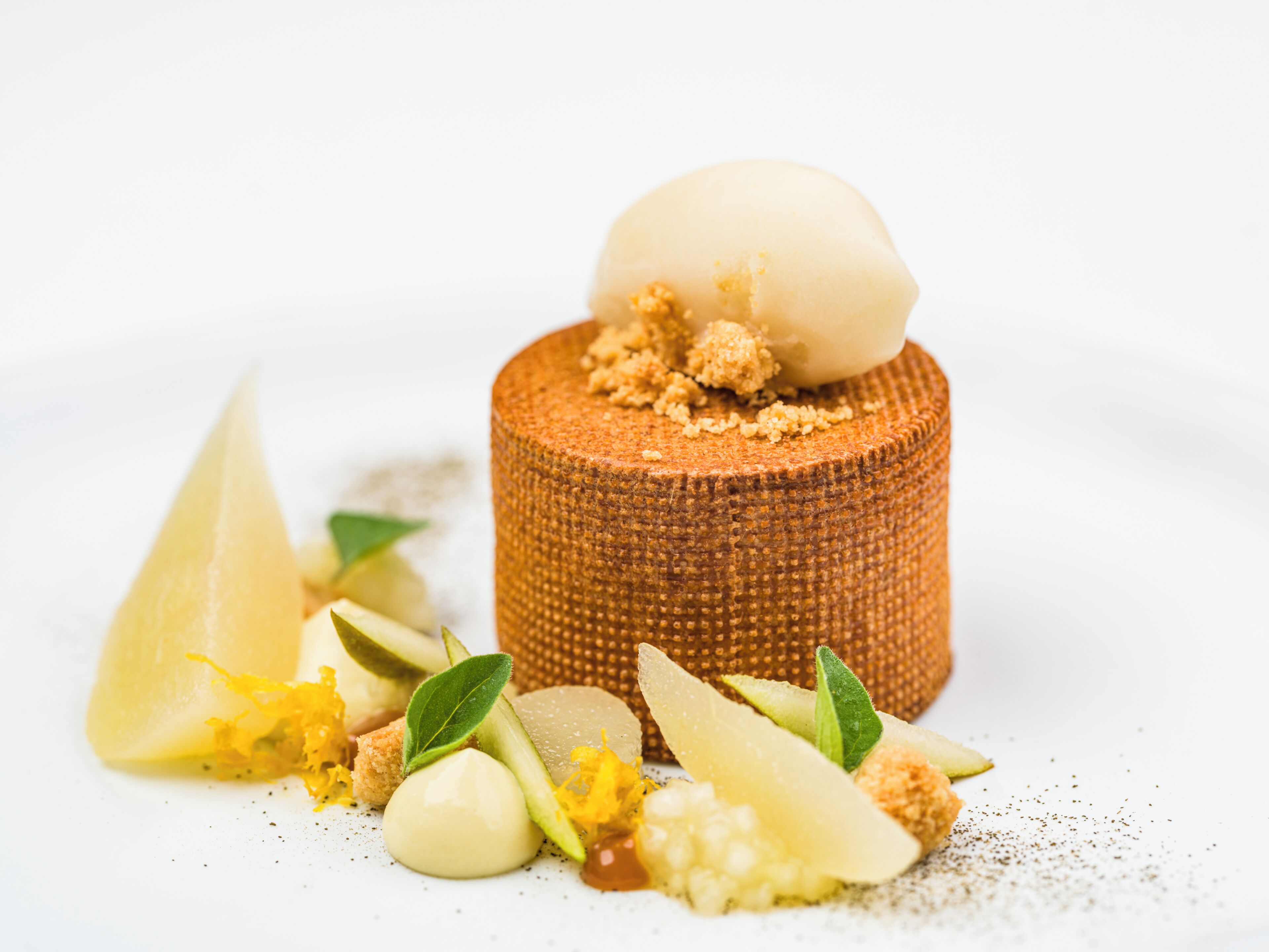 Un postre con base texturizada y una porción de helado encima, rodeado de diferentes adornos.