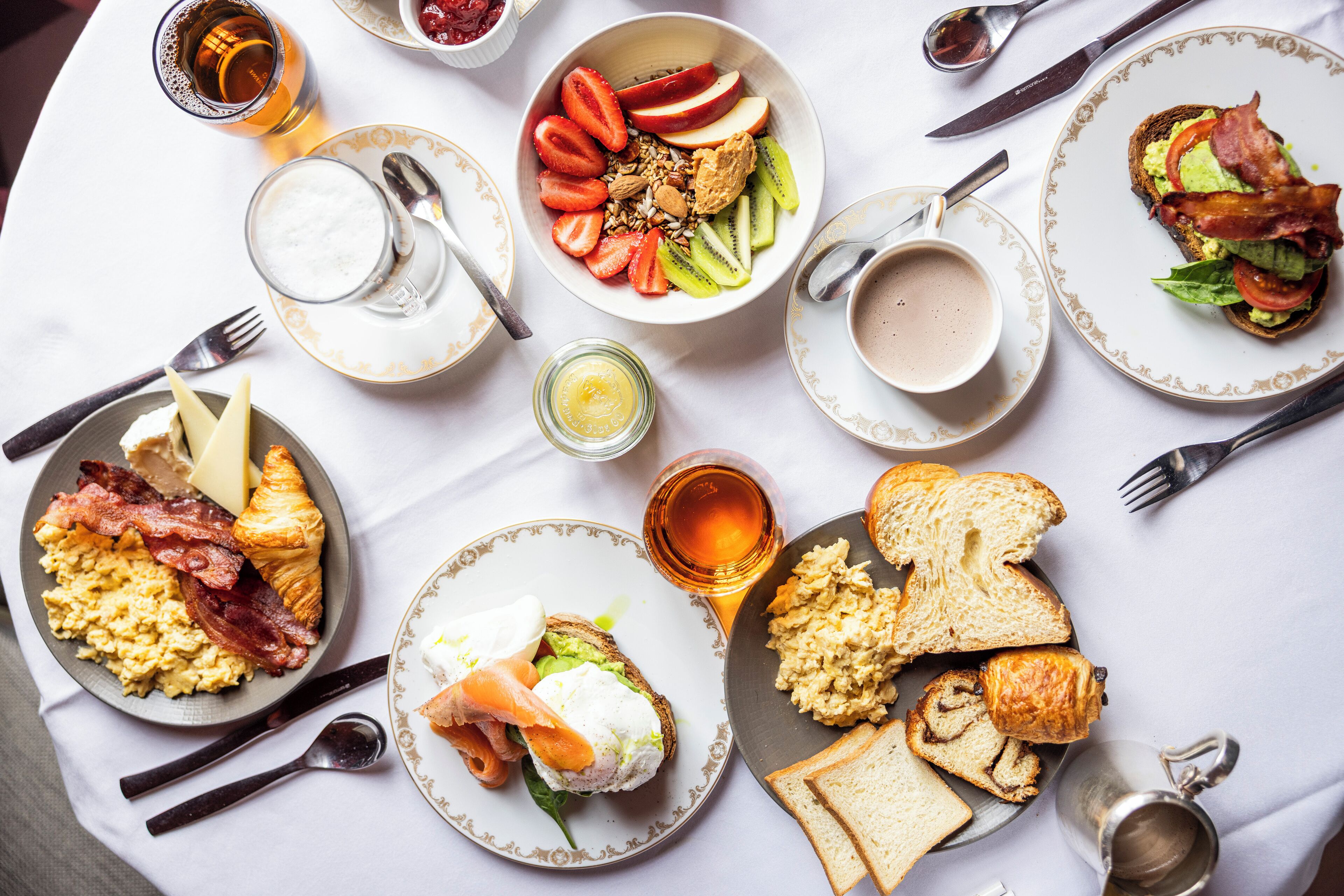 A breakfast setting with various dishes, utensils, and a cup of coffee.