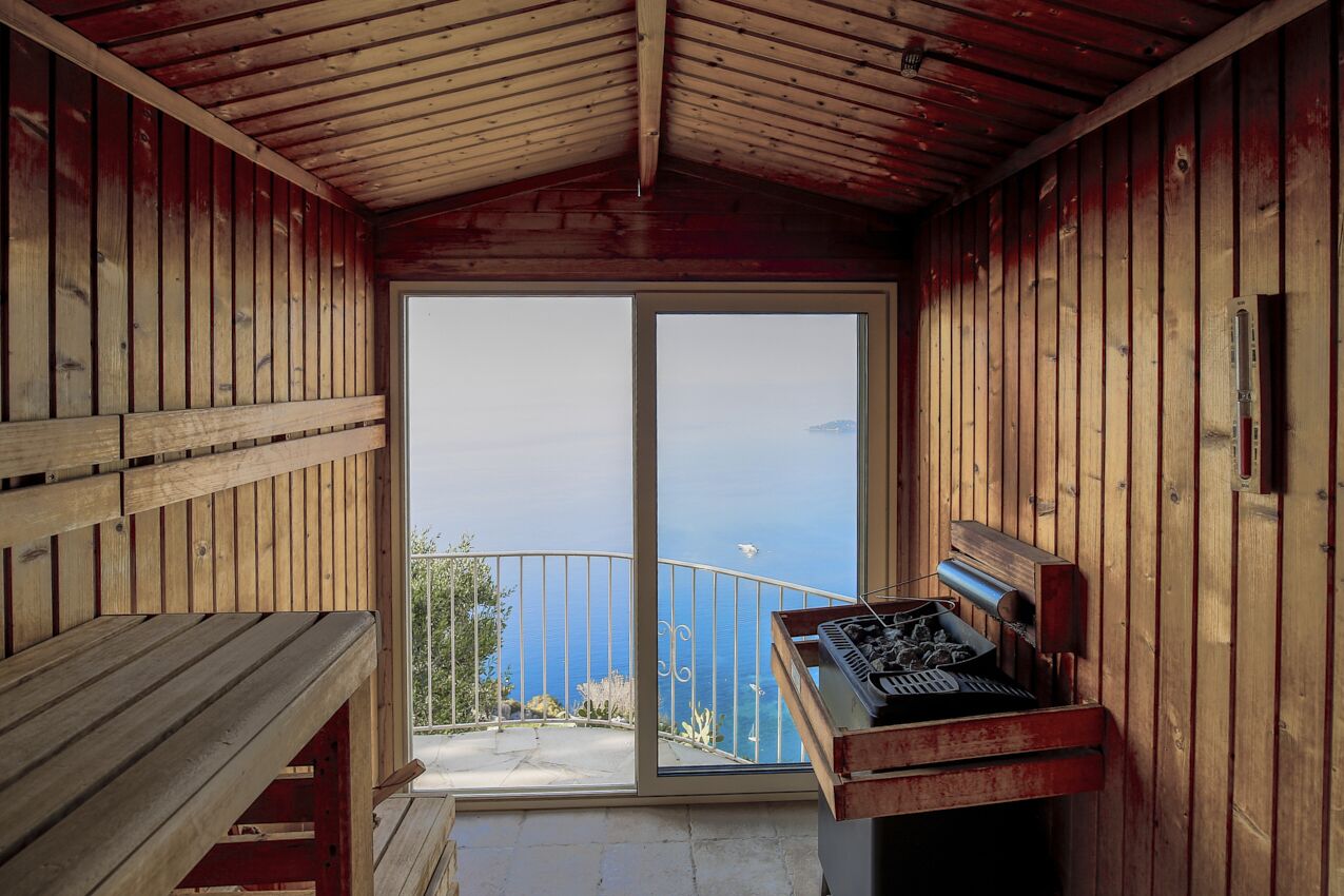 A wooden cabin with a sliding glass door leading to a balcony with a view of the sea.