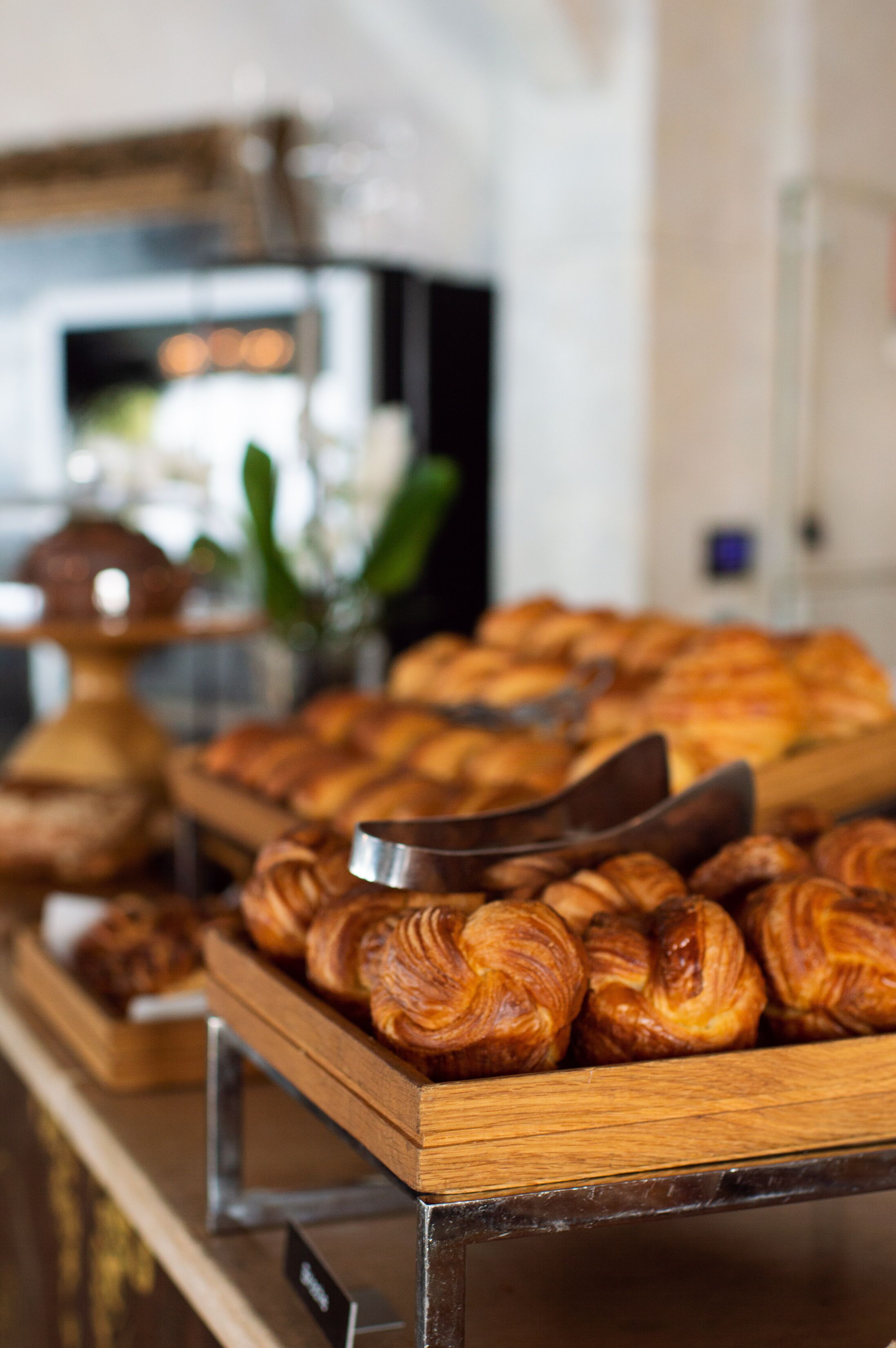 A display of pastries on a wooden tray in a bakery setting.