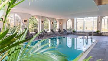 A swimming pool with lounge chairs and arched windows.