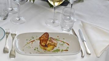 Une table à manger dressée avec une assiette de nourriture, des couverts et des verres.
