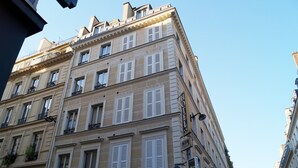 Un edificio a più piani con uno stile architettonico classico, caratterizzato da persiane bianche alle finestre e una insegna che indica che si tratta di un albergo.