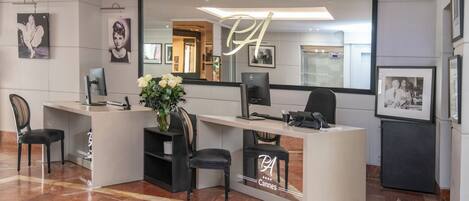 A reception desk with a large mirror, framed pictures on the walls, and a vase with flowers.