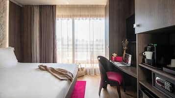 A hotel room with a bed, a desk, a chair, a coffee machine, and a TV.