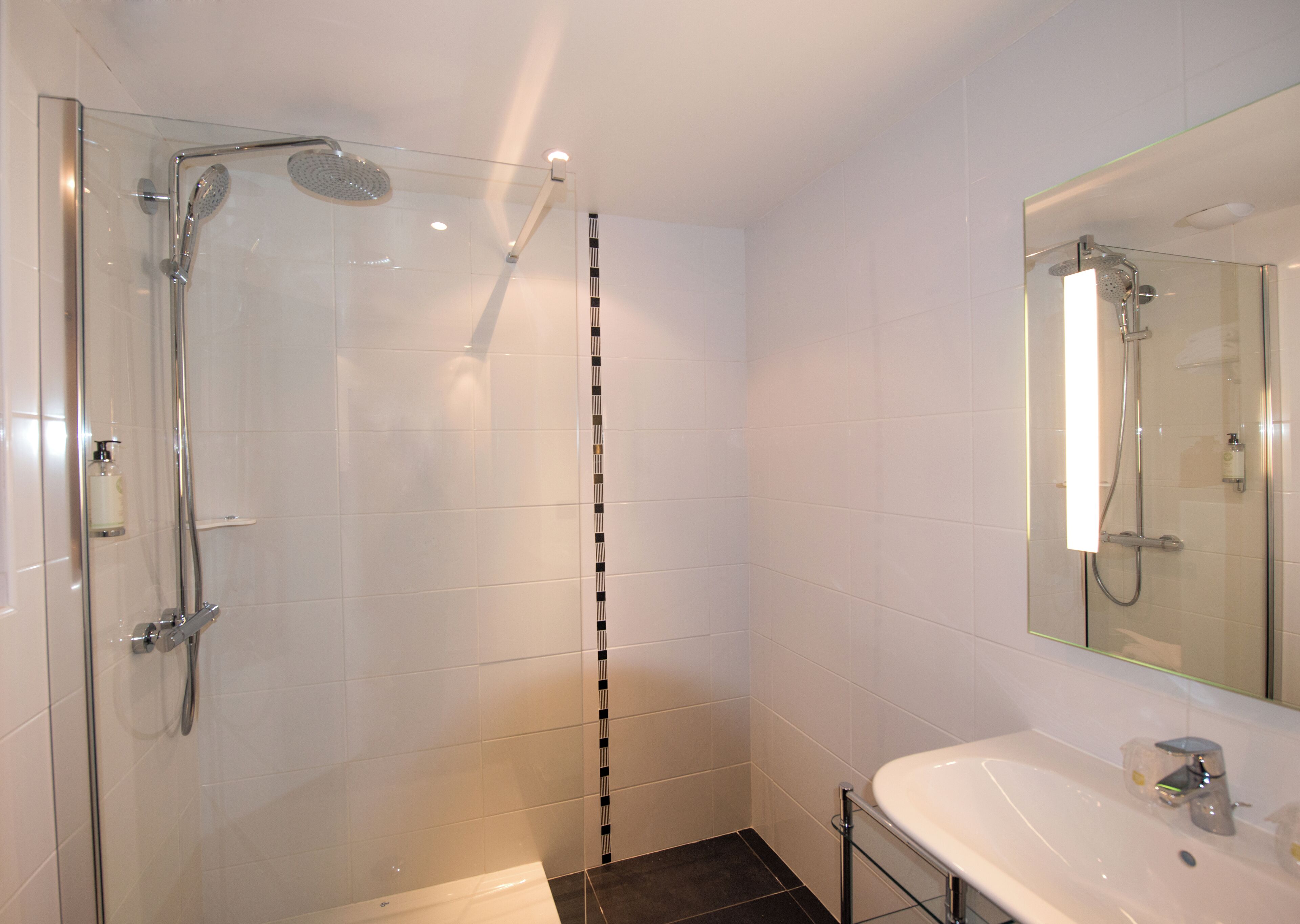 A modern bathroom with a glass-enclosed shower, a white sink, and a mirror above the sink.