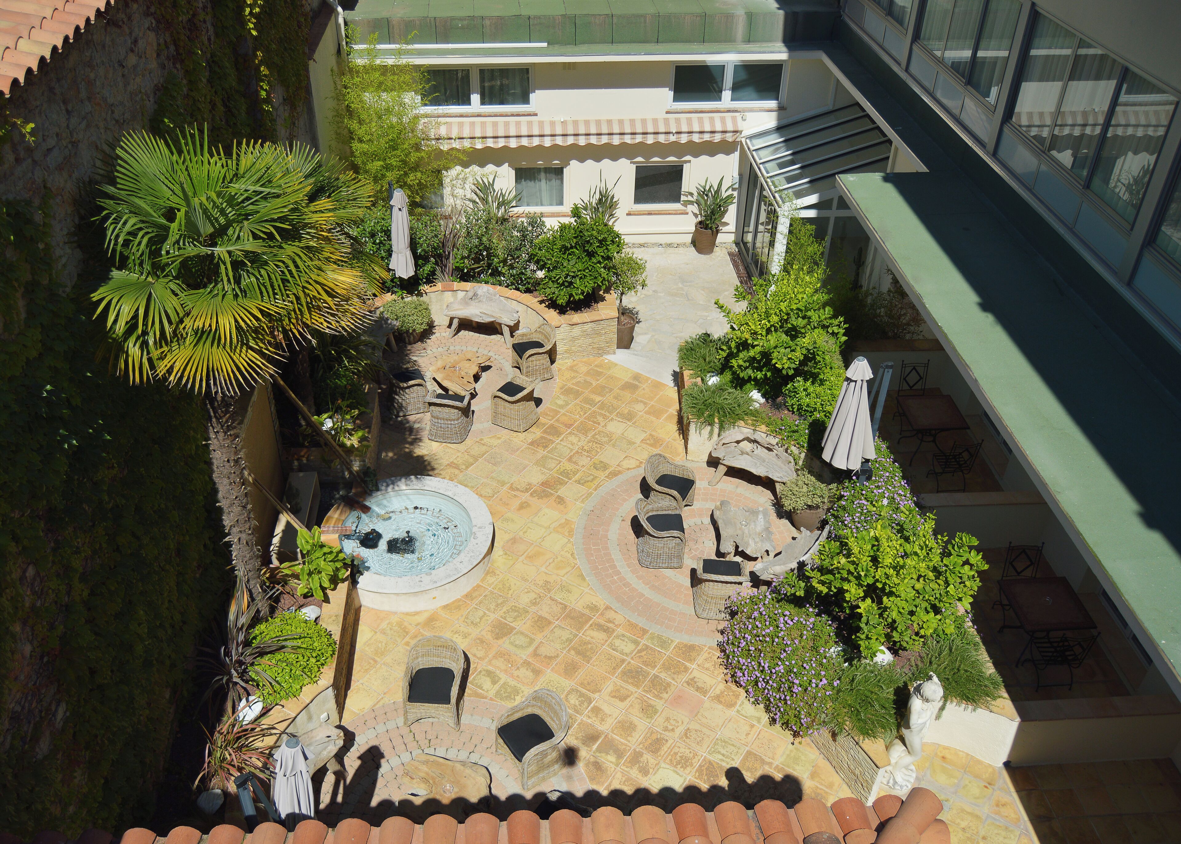A courtyard with outdoor seating, a hot tub, and potted plants.