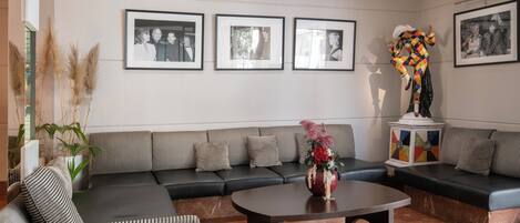 A modern living room with a dark-colored sofa, striped armchair, and a coffee table. There are framed photographs on the wall and a decorative vase on the table.