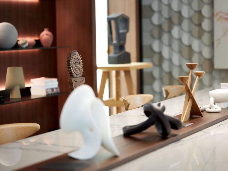 A modern kitchen with a marble countertop, wooden chairs, and various kitchen utensils.
