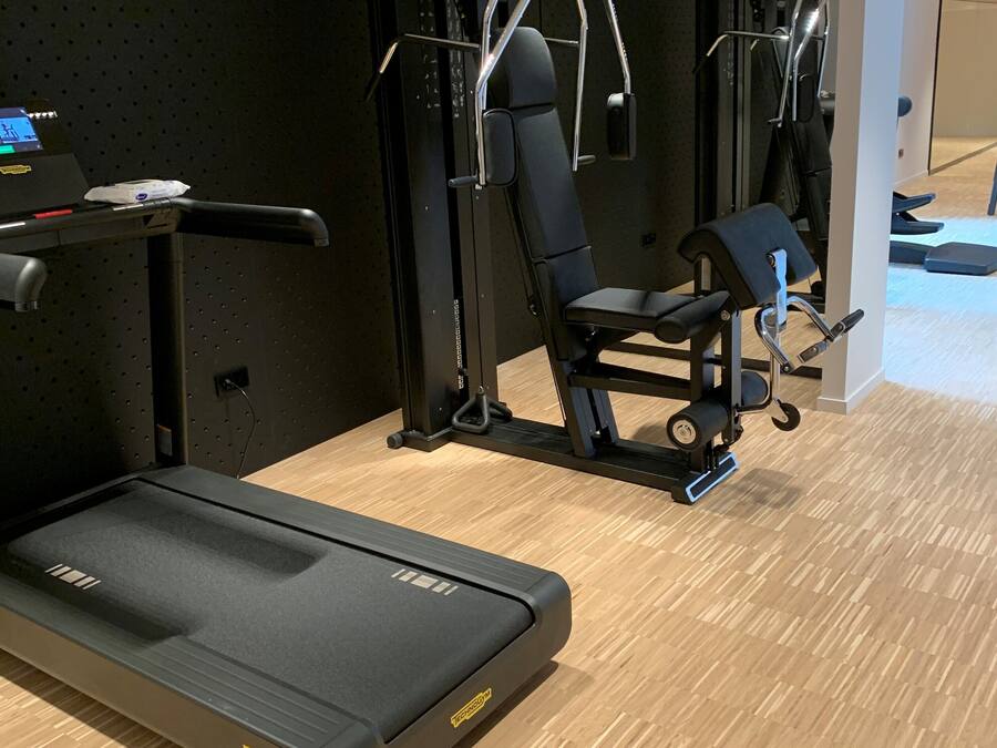 A gym with a treadmill, weight machines, and a pull-up bar.