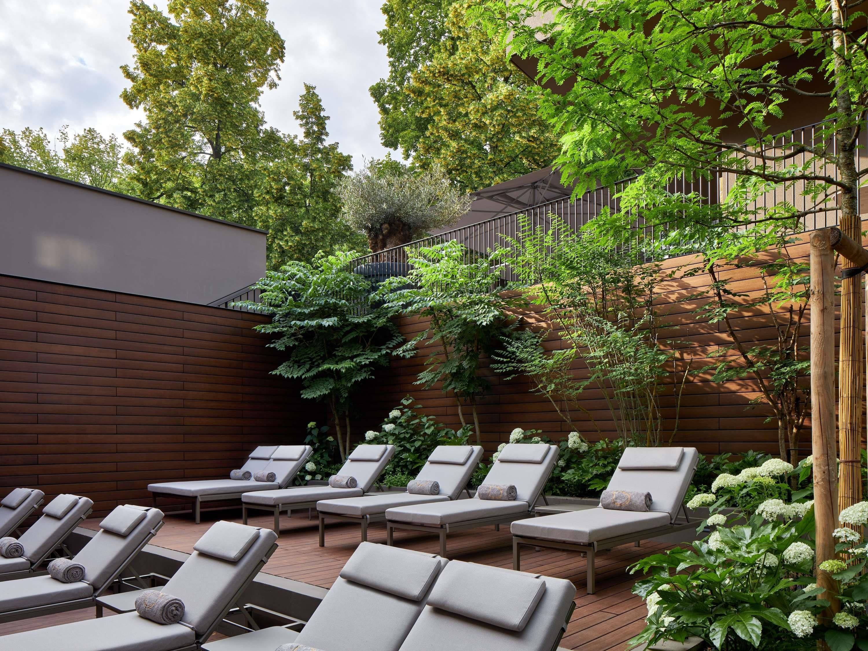 Un patio con sillones de sol, una pared de madera y una valla de metal.