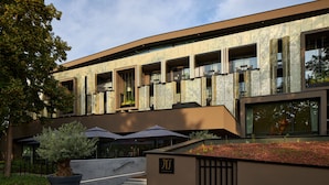 A modern building with a flat roof, large windows, and a landscaped area with potted plants and umbrellas. - L'Esquisse Hotel & Spa Colmar - MGallery Collection (Colmar)