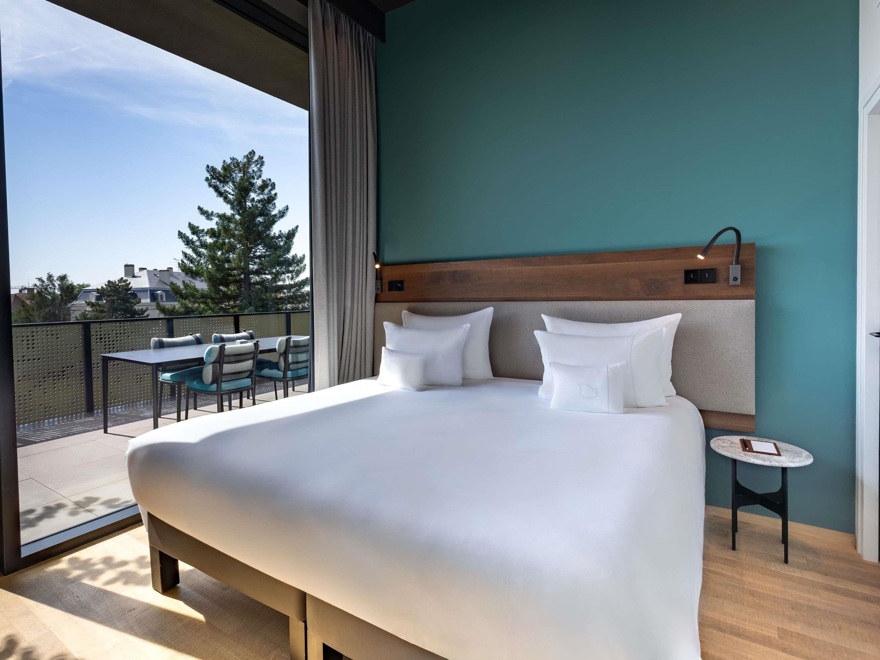 Ein Hotelzimmer mit einem großen Bett, einem kleinen Tisch und einem Balkon mit Sitzgelegenheit.