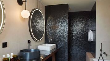 A modern bathroom with a round mirror, a rectangular sink, a bathtub, and a shower area.