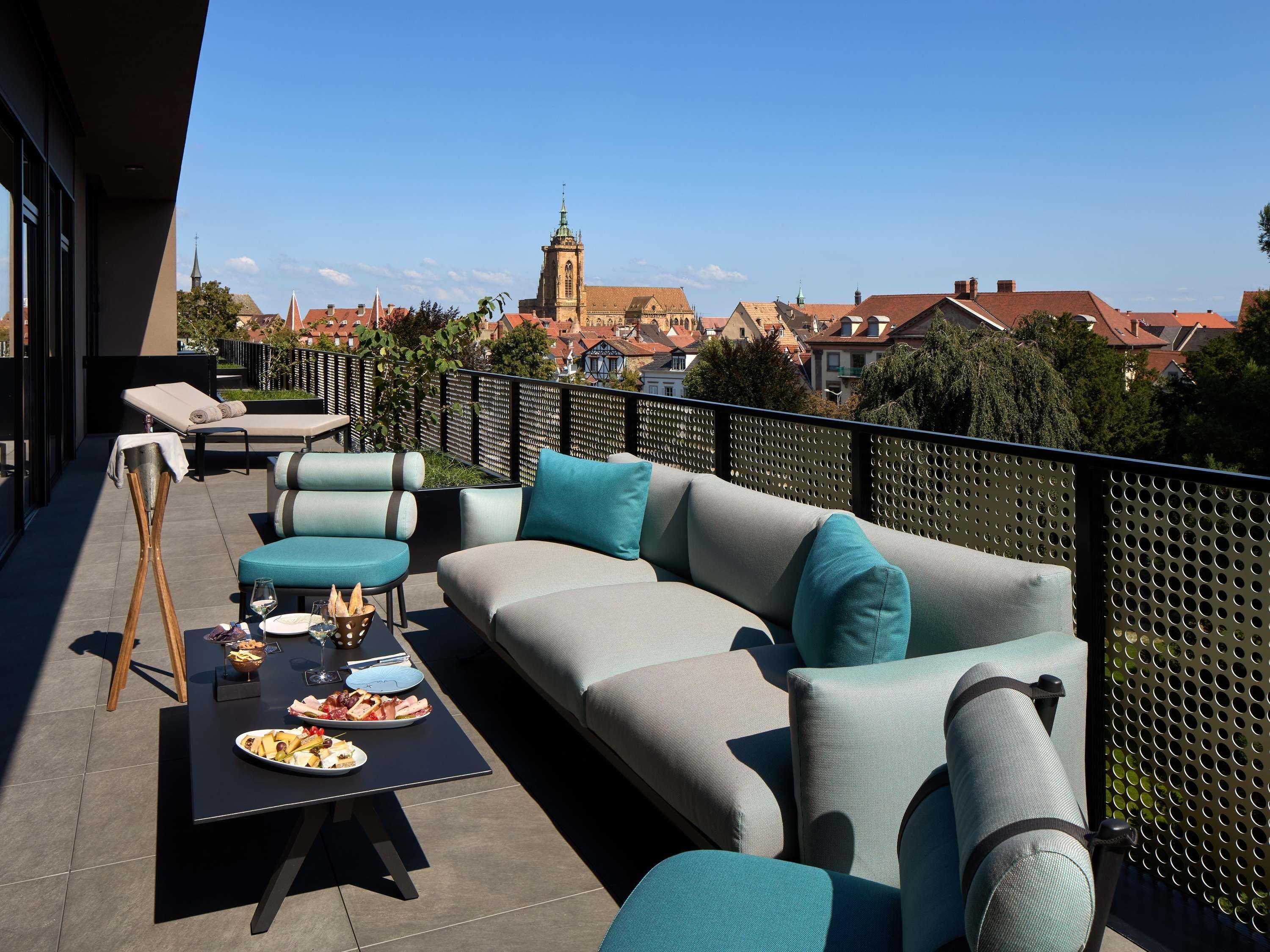 Terraza en la azotea con un conjunto de sofás, una mesa de comedor y vistas a una torre de iglesia.
